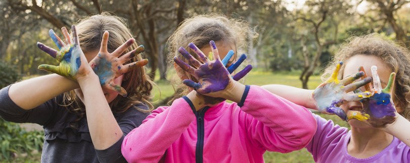 Enfants qui cachent leur visage avec les mains pleines de peinture