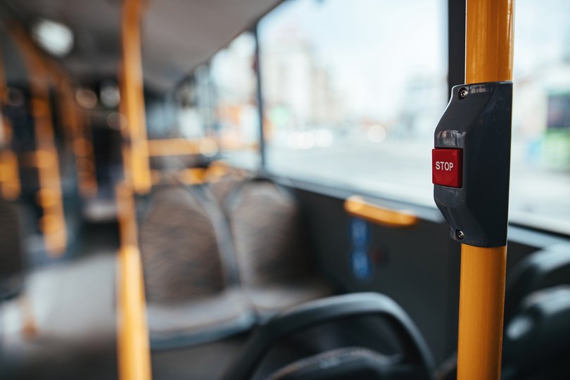 Bouton d'arrêt dans un bus en premier plan avec des siège en fond