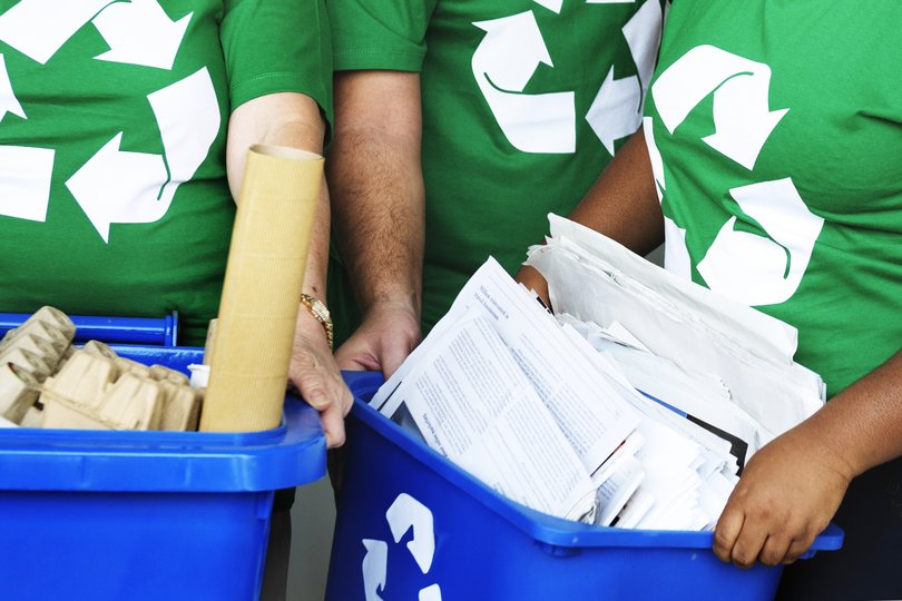 Personnes tenant des bacs pour trier les déchets. Elles ont des t-shirt avec le logo recyclage